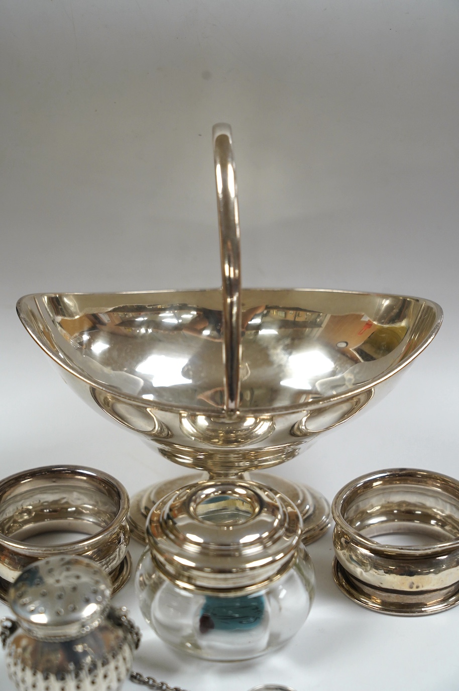 An Edwardian silver boat shaped sugar basket, by Thomas Bradbury & Sons, London, 1905, 13.9cm, together with two silver napkin rings, mounted glass hair tidy and a sterling pomander. Condition - poor to fair